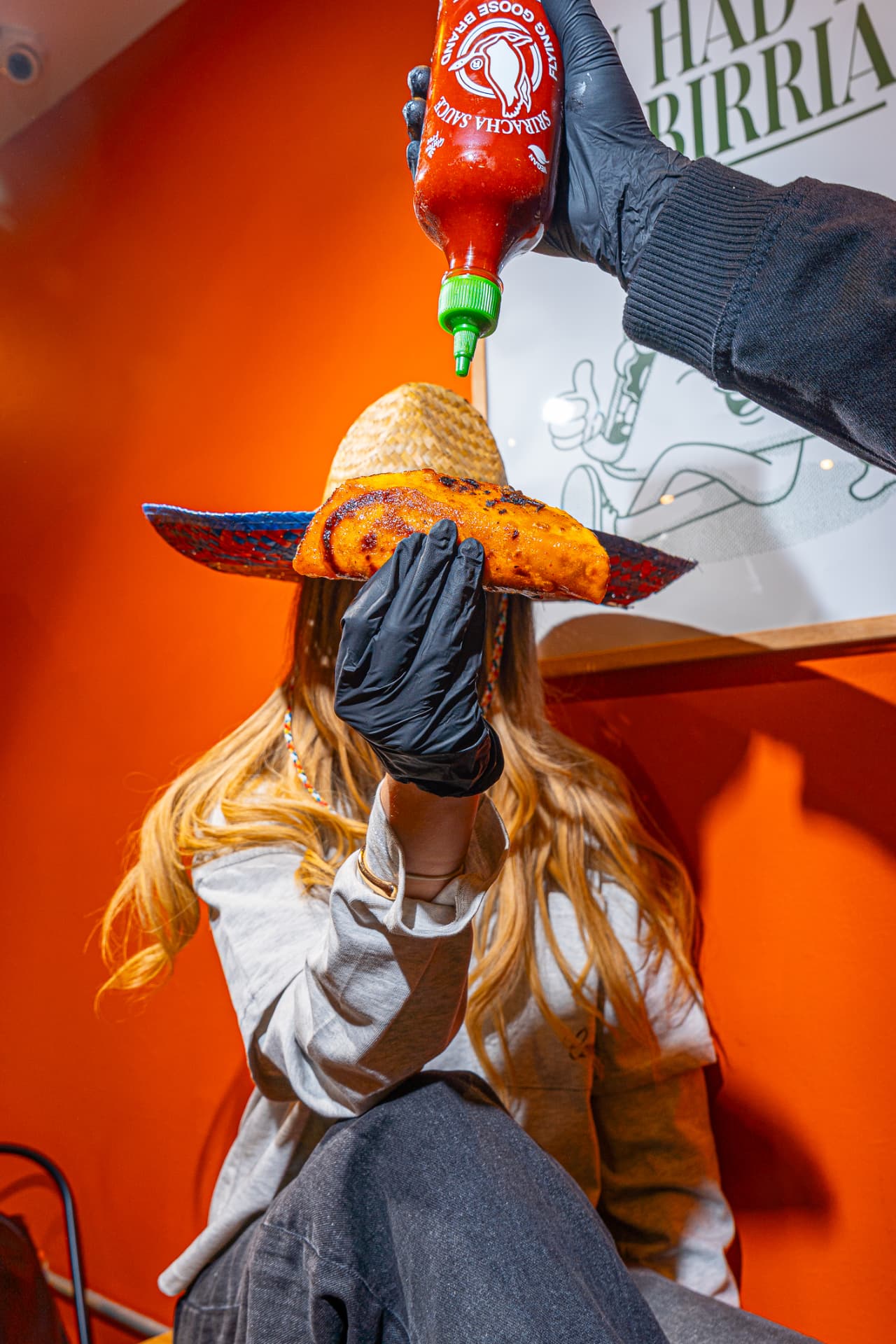 Sriracha poured over a birria taco, food photography in Leeds